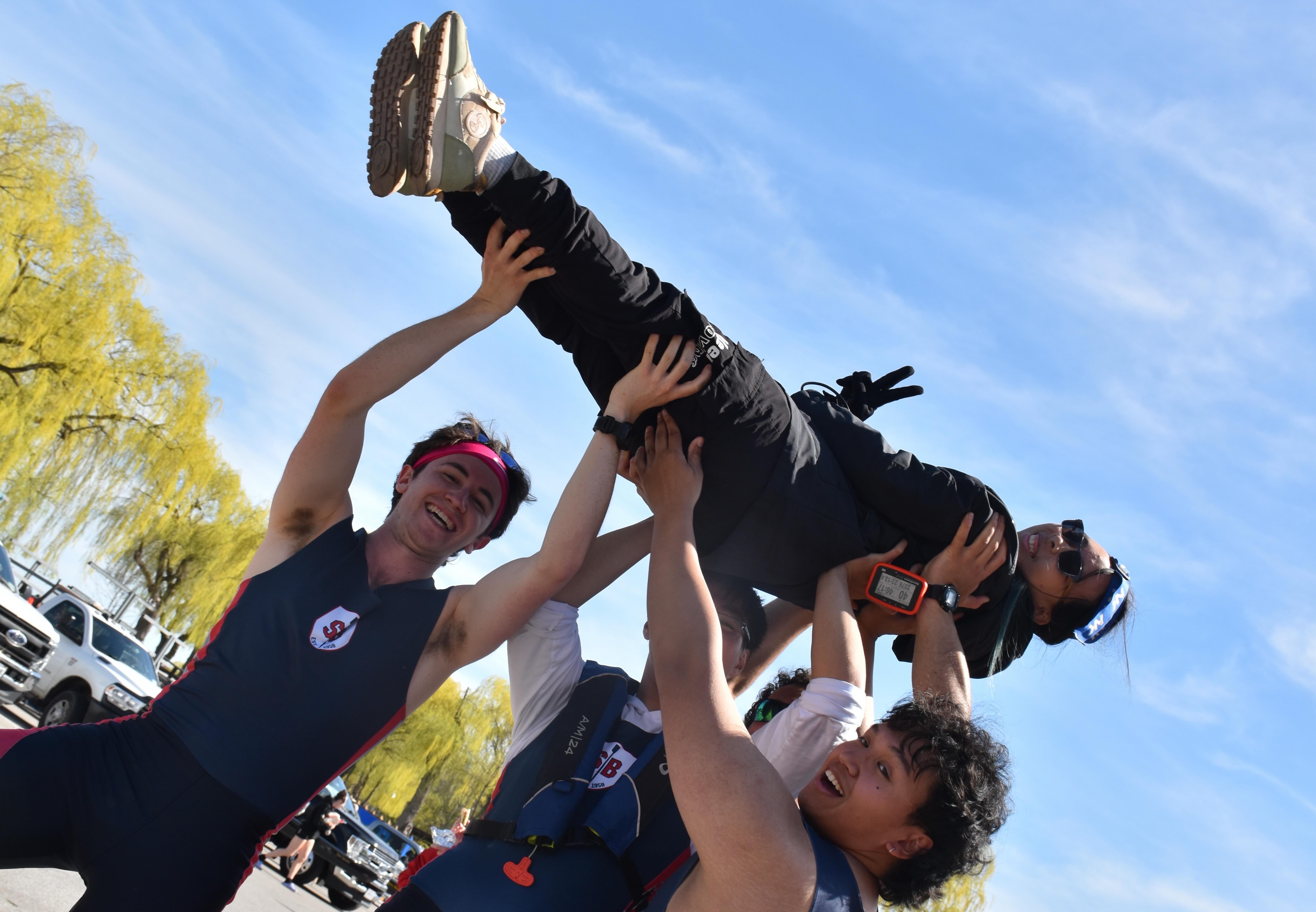 Men's Varsity 4 raising their coxswain.